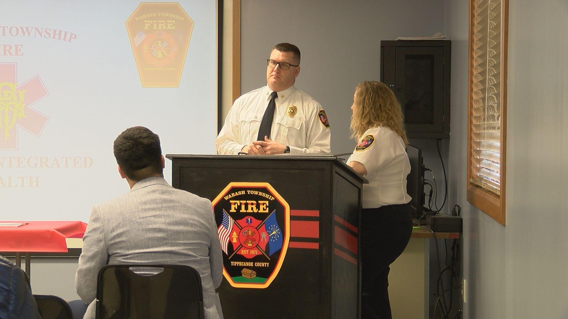 Two personnel members of Wabash Township Fire stand at a lectern during a meeting.