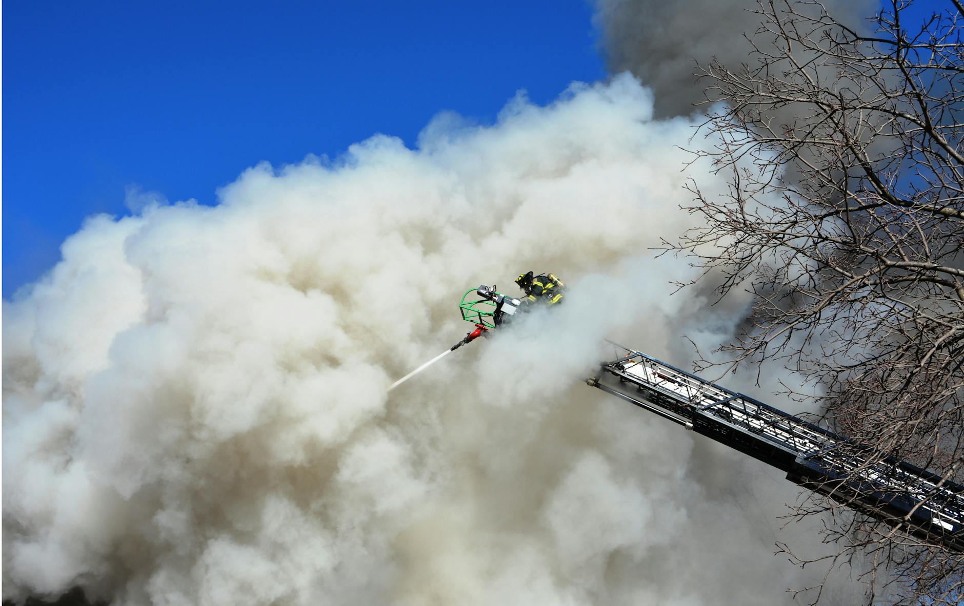 firefighters battling large smoke cloud from ladder