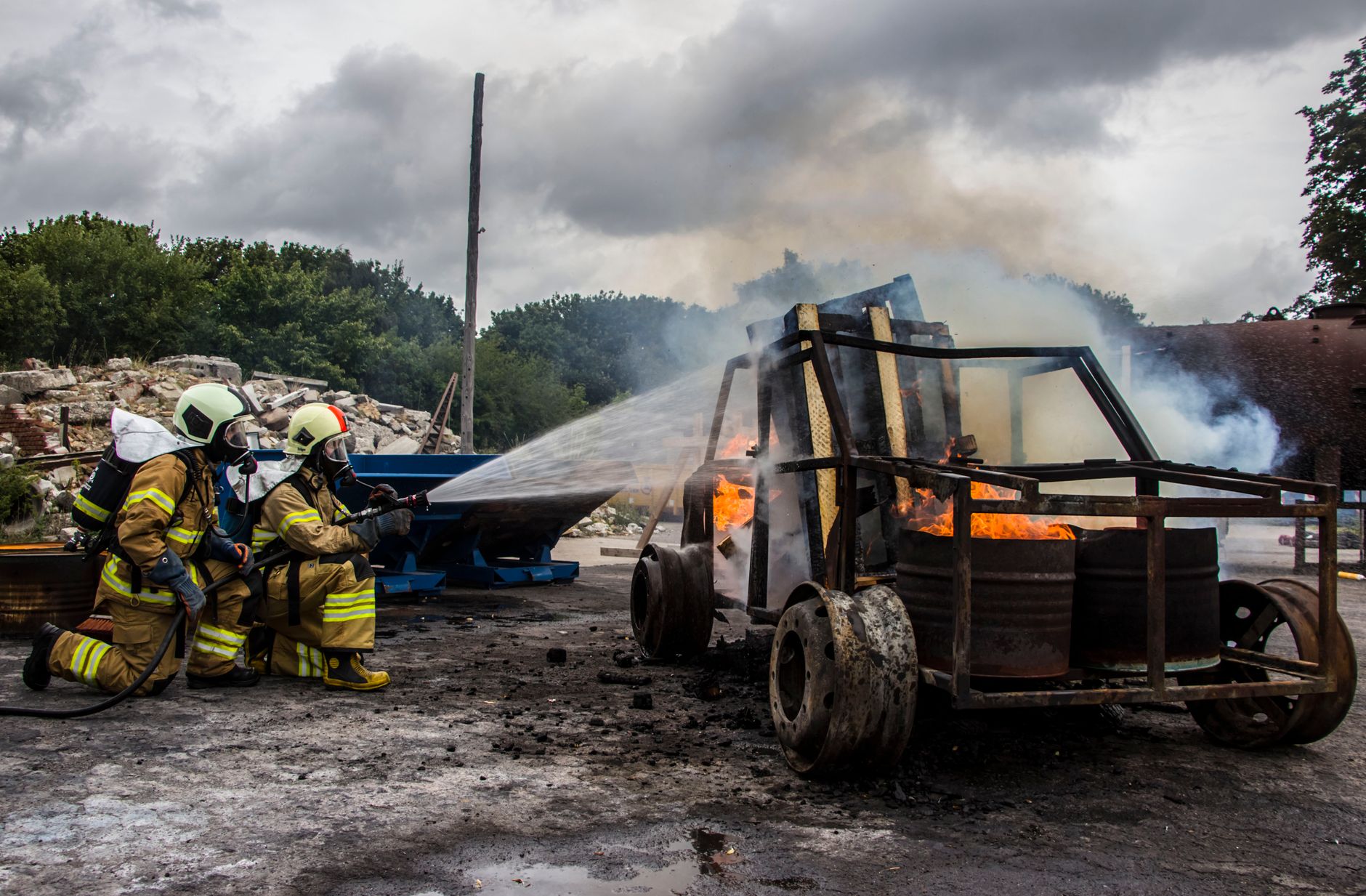 two firefighters extinguish a car