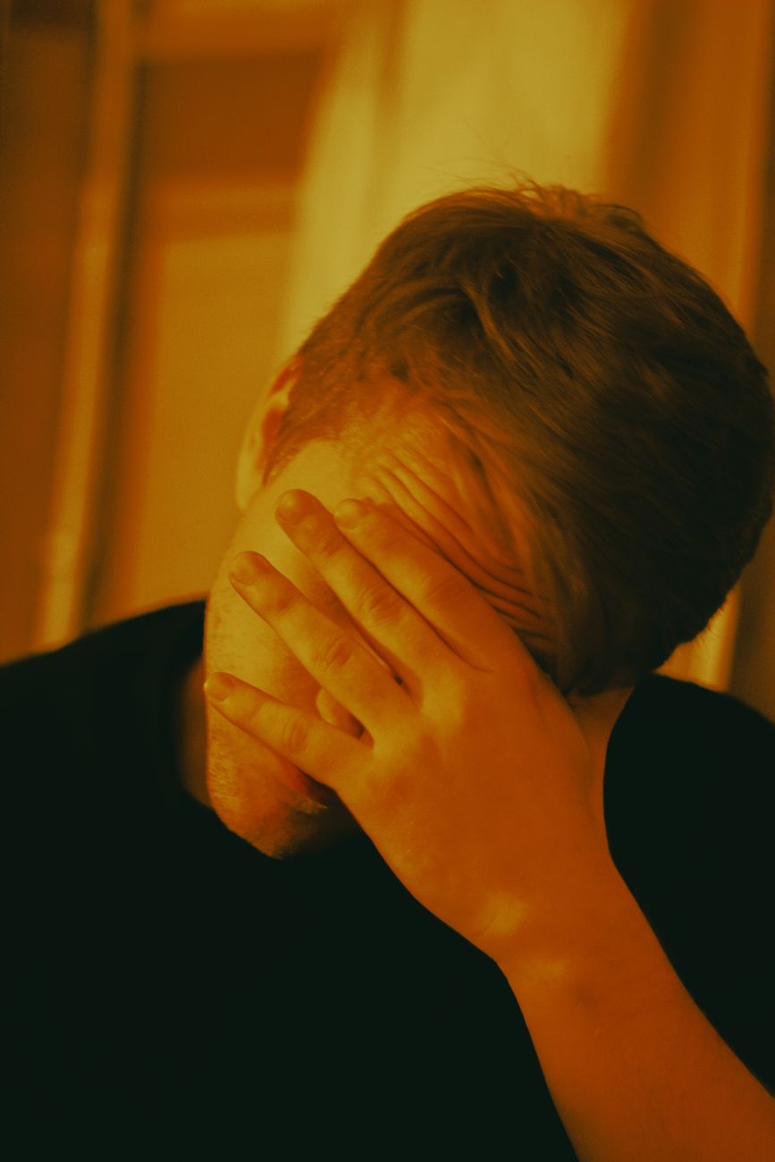 man in black shirt covering his face