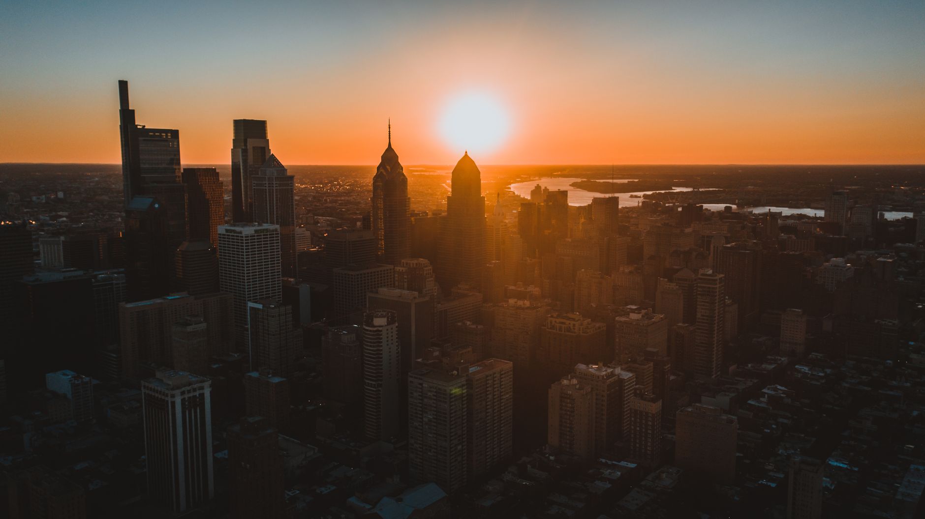 skyscrapers near endless sea under sky with bright sun